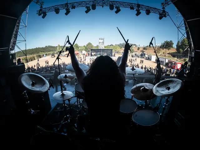 From behind the drum kit: the drummer with sticks raised over the festival crowd